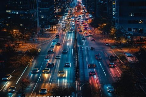 都市夜晚俯拍街道车流光轨，象征人妻猎人中婚姻猎场的流动与不确定性，冷暖色调交织氛围感强烈